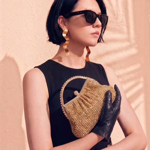 SUL EXTRAS Estelle evening bag in gold rhinestone with arched handle, held by a woman in black dress and gloves.