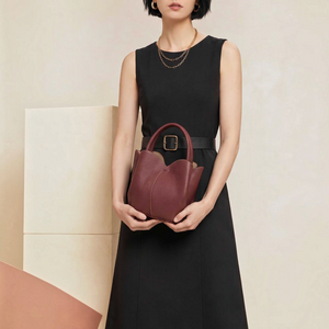 SUL EXTRAS Tulipe 2-in-1 burgundy grained synthetic tote bag with petal-inspired curves held by a woman in black dress