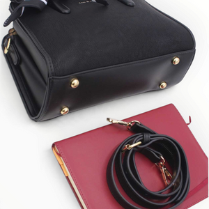 SUL EXTRAS Tom & Eva Juliette black handbag with gold feet, scarf, and detachable shoulder strap on a red notebook