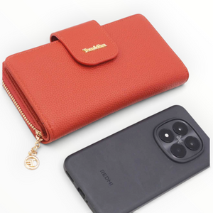 SUL EXTRAS Léonie wallet in red pebbled leather-effect with gold-tone hardware and snap closure next to a smartphone