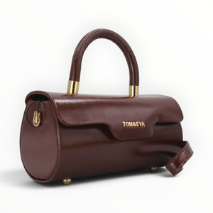 SUL EXTRAS Tom & Eva brown patent-effect barrel handbag with gold-tone hardware and a structured top handle.