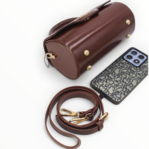 SUL EXTRAS Tom & Eva brown patent barrel handbag with gold hardware, detachable strap, and metal feet on base.