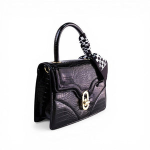 SUL EXTRAS black crocodile-embossed top-handle bag with gold hardware and a patterned scarf tied to the handle