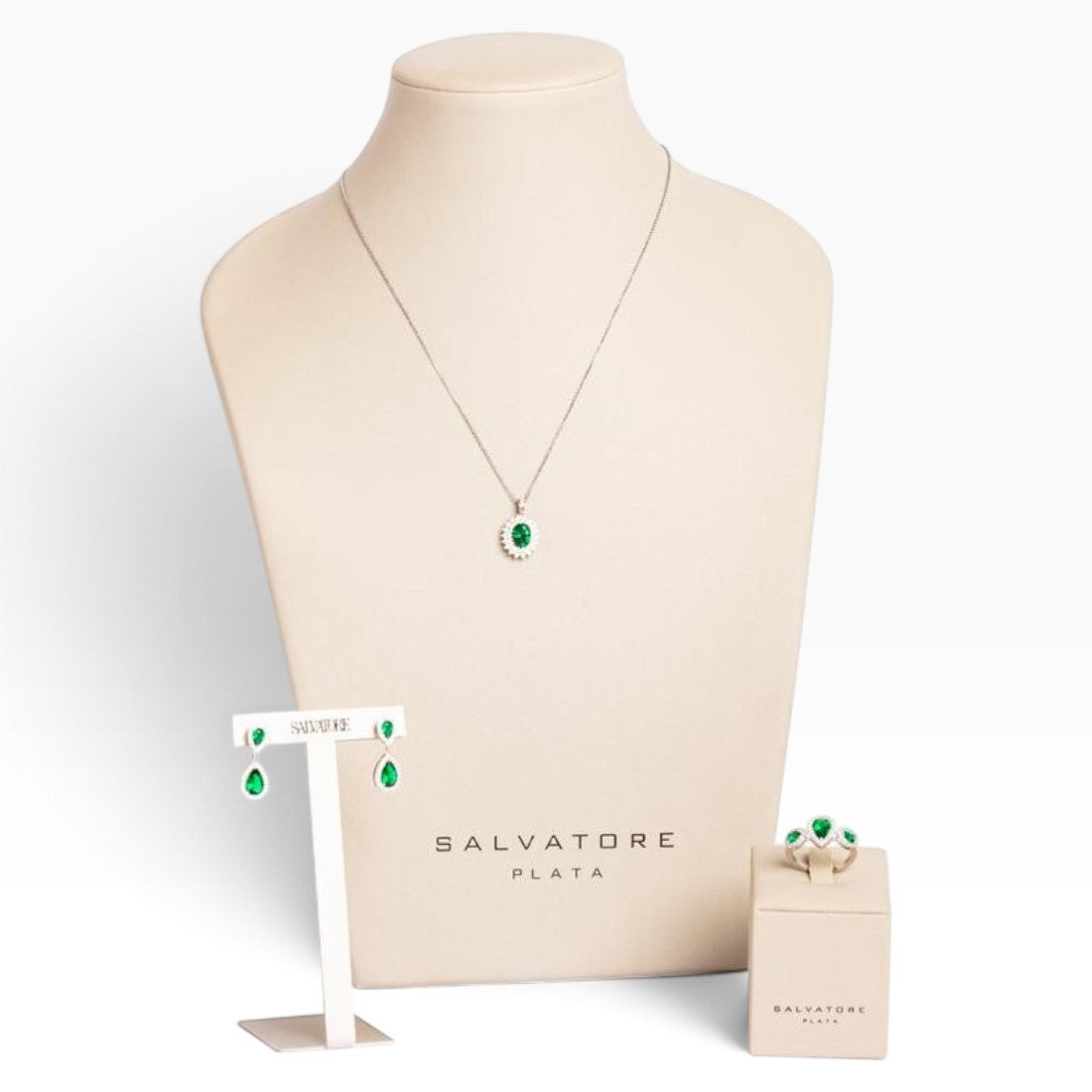 SUL EXTRAS jewelry set featuring an oval halo necklace, pear drop earrings, and three-stone ring in silver and green.