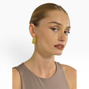 Model wearing SUL EXTRAS gold ribbed hoop earrings from the Grace Set, featuring a sculptural and architectural design.