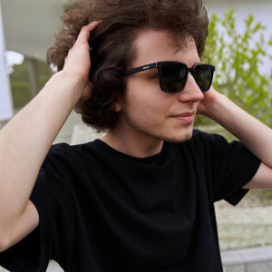 A man wearing SUL EXTRAS Leo polarized sunglasses with a black lightweight frame and dark lenses.