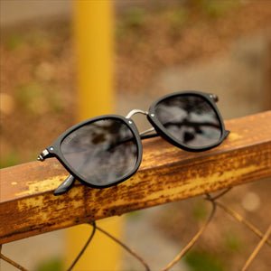 SUL EXTRAS Visi sunglasses featuring a shiny black rectangle frame with green lenses and metal stud accents.