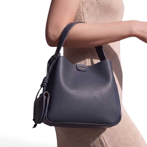 SUL EXTRAS Tom & Eva Noémie bucket bag in dark grey grained synthetic leather with knotted detail and key charm.
