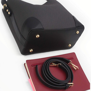 SUL EXTRAS Margot bucket bag in black grained synthetic leather with gold hardware, short handle, and long strap.