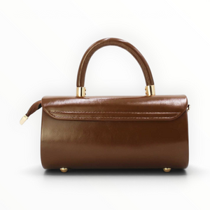 SUL EXTRAS brown patent-effect barrel handbag with gold-tone hardware, top handle, and protective metal base feet.