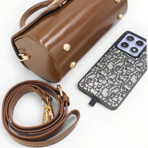 SUL EXTRAS Tom & Eva Colette brown barrel handbag with gold hardware, detachable strap, and phone for scale.