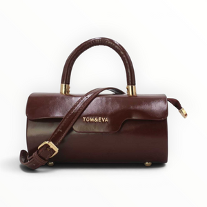 SUL EXTRAS Tom & Eva brown patent barrel handbag with gold-tone hardware, top handle, and adjustable shoulder strap.