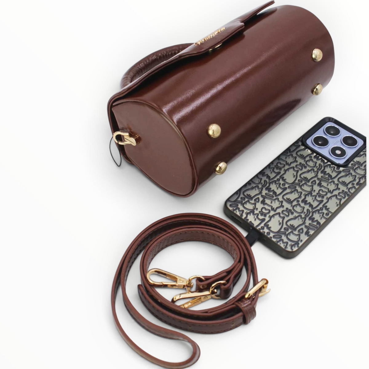 SUL EXTRAS Tom & Eva brown patent barrel handbag with gold hardware, detachable strap, and metal feet on base.