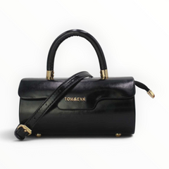 SUL EXTRAS Tom & Eva black patent barrel handbag with gold-tone hardware, top handle, and adjustable shoulder strap.