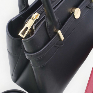 SUL EXTRAS Tom & Eva black structured handbag with gold-tone hardware, twin handles, and decorative belt detail.