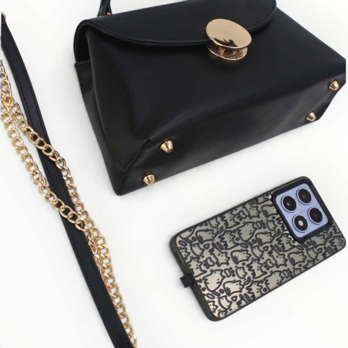 SUL EXTRAS Tom & Eva black structured handbag with gold hardware, top handle, and chain strap next to a patterned phone