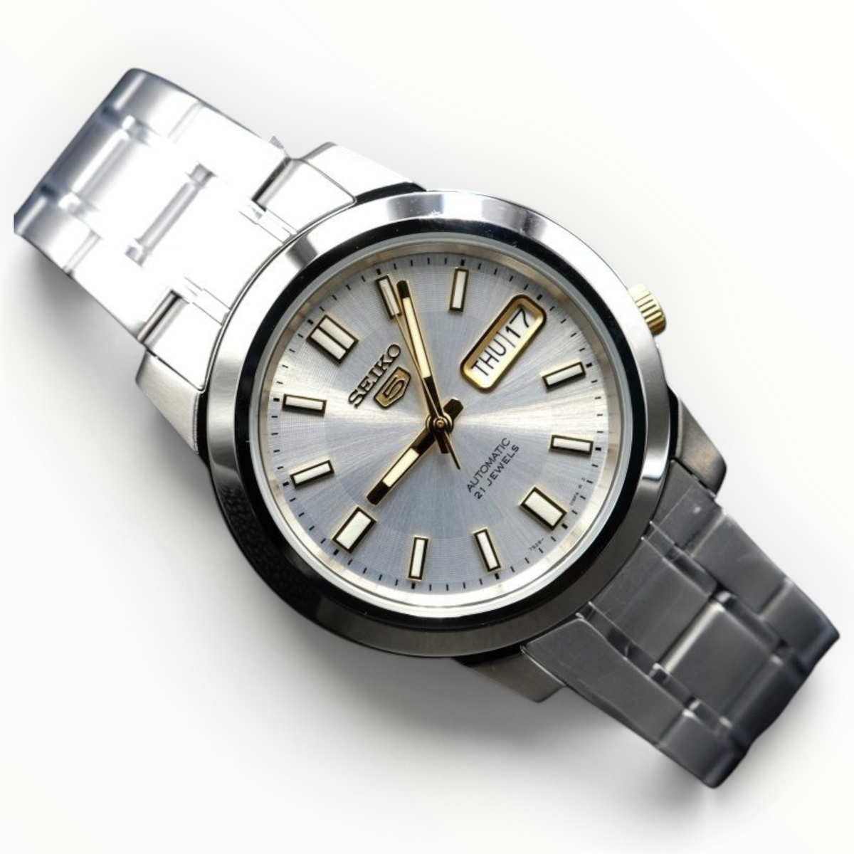 SUL EXTRAS Seiko 5 automatic watch with a silver sunray dial, gold-tone hands, and a stainless steel bracelet.