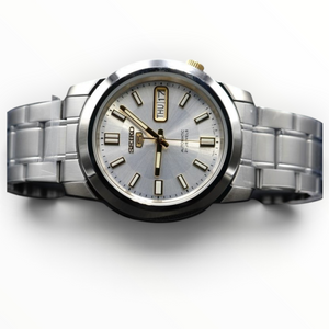 SUL EXTRAS Seiko 5 automatic watch with a silver dial, stainless steel bracelet, and gold-tone hands and markers.