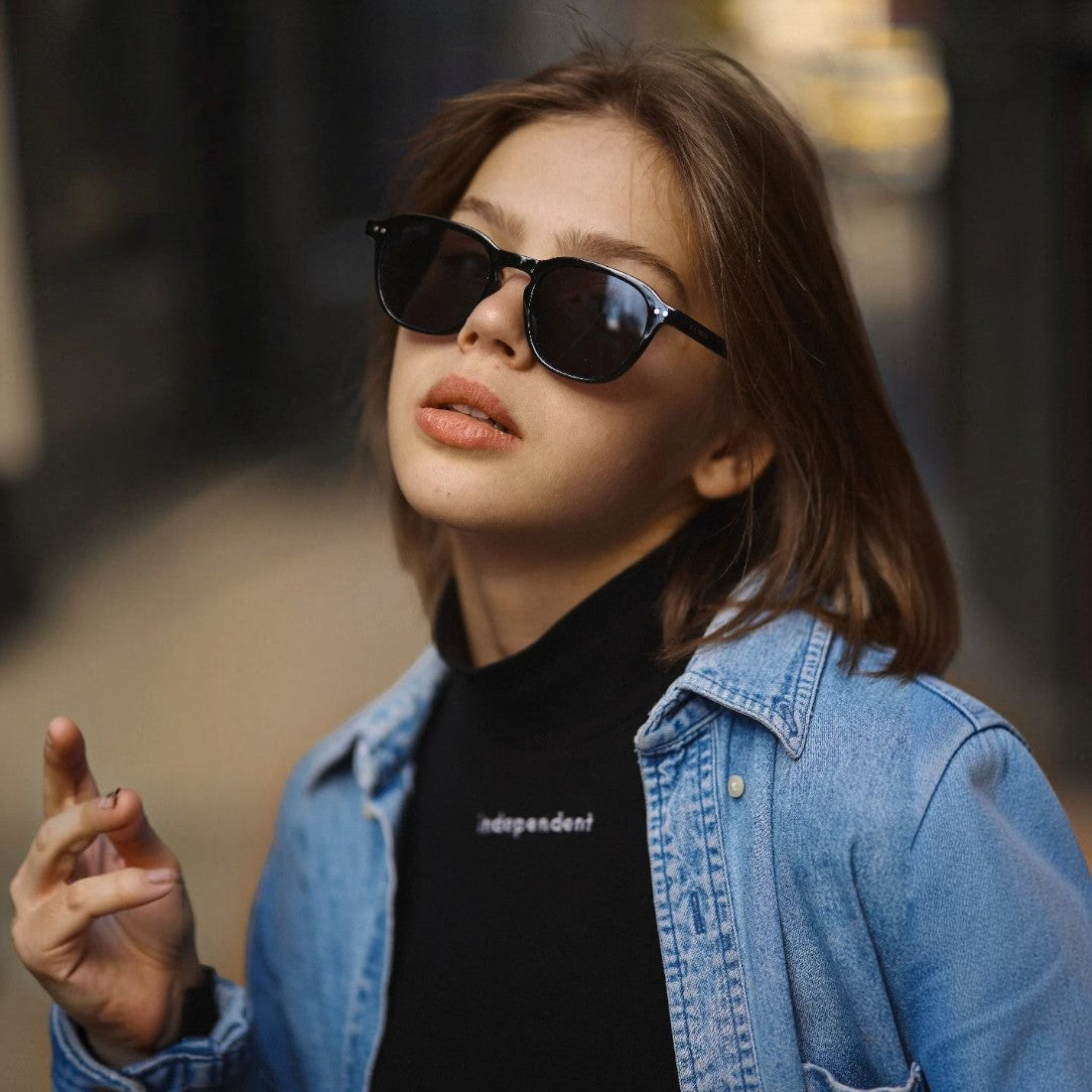 A woman wearing SUL EXTRAS Ace black sunglasses with impact-resistant lenses and a durable lightweight frame.