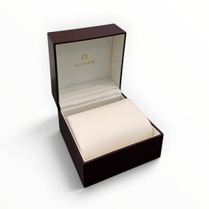 SUL EXTRAS Aigner luxury watch gift box in deep burgundy lacquer with a cream interior cushion and gold logo branding.