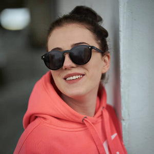 A woman wearing SUL EXTRAS aviation sunglasses with polarized lenses and a sleek black metal frame.