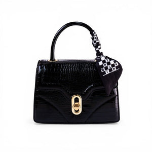 SUL EXTRAS black crocodile-embossed top-handle bag with a gold clasp and a decorative black and white patterned scarf