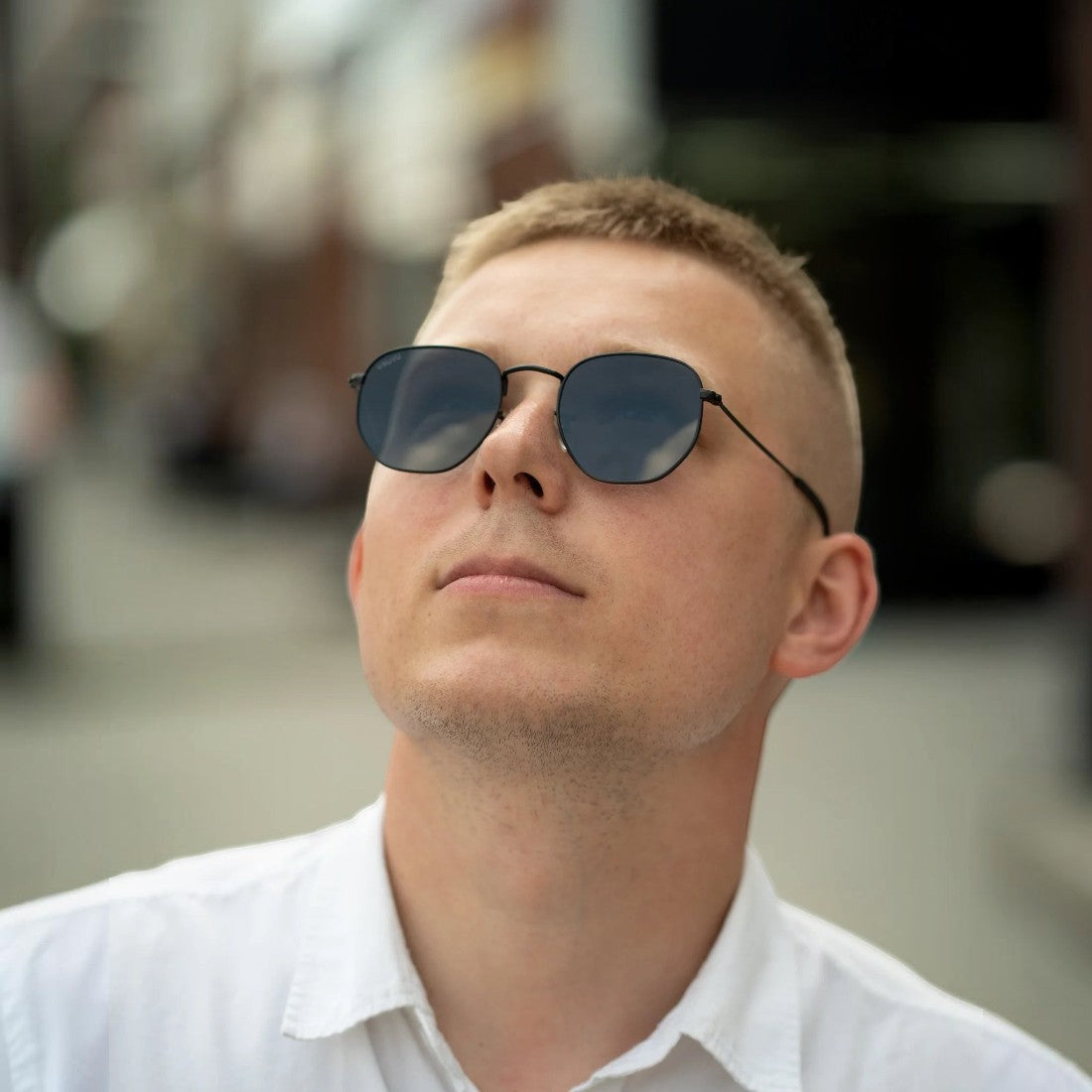 SUL EXTRAS Eternally minimalist geometric sunglasses with black metal frames worn by a man in a white shirt