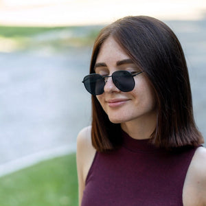 SUL EXTRAS Eternally minimalist geometric sunglasses with black metal frames worn by a woman with dark hair.
