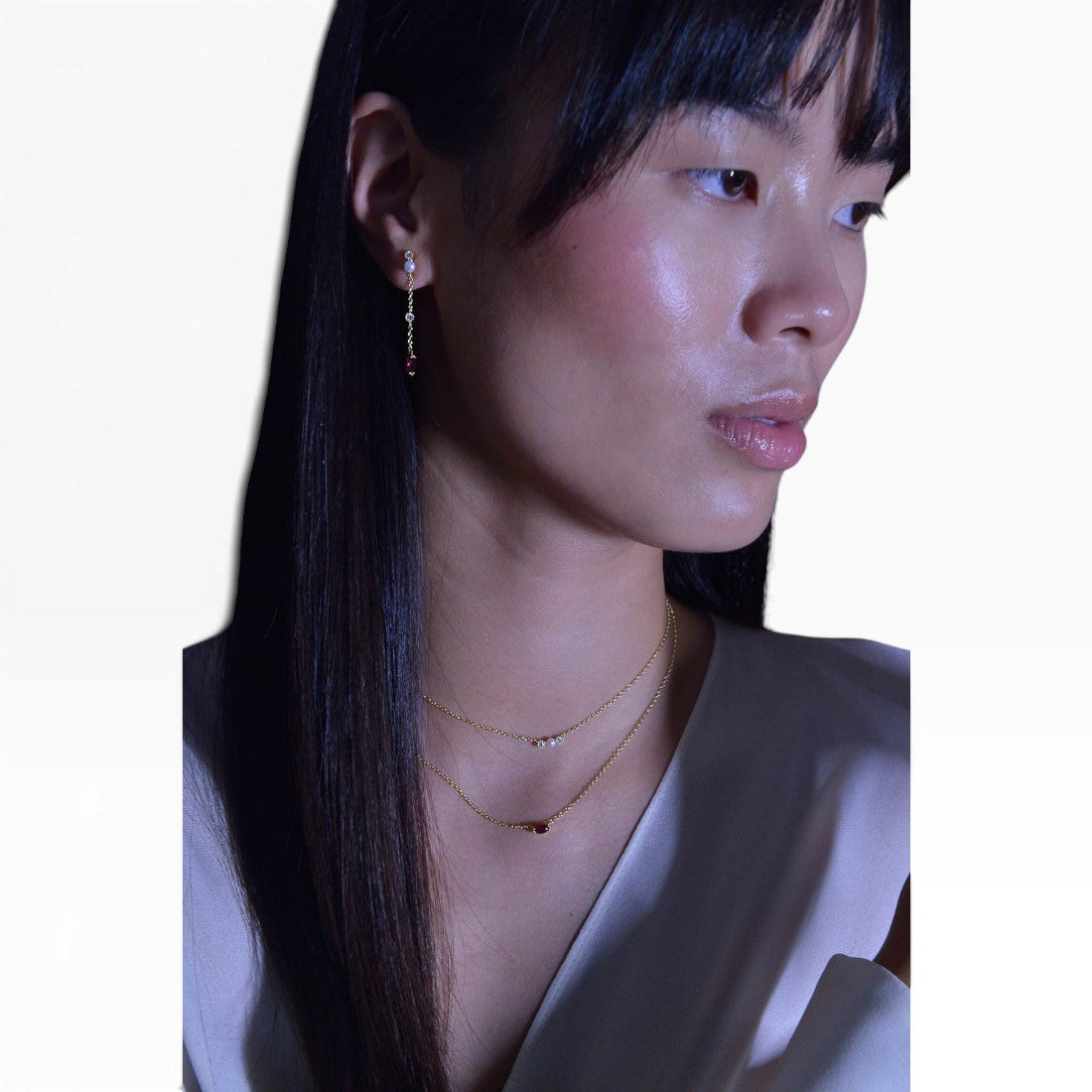 SUL EXTRAS gold-plated layered necklace and pearl earrings worn by a model, featuring red zirconia accents.