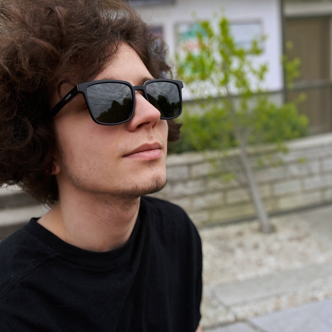 A man wearing SUL EXTRAS Leo black polarized sunglasses with a durable frame and scratch-resistant lenses.