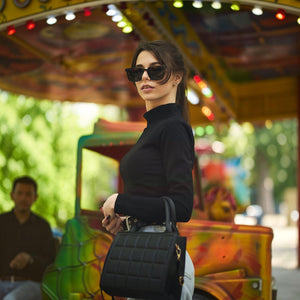 Woman wearing SUL EXTRAS Leo polarized sunglasses with a black frame at a carnival