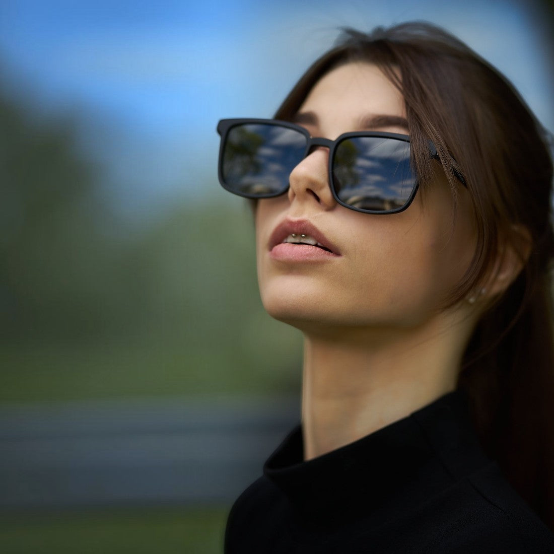 Woman wearing SUL EXTRAS Leo polarized sunglasses with black frames and dark lenses outdoors
