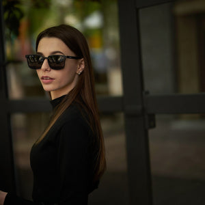 Woman wearing SUL EXTRAS Leo polarized sunglasses with black frames and scratch-resistant lenses