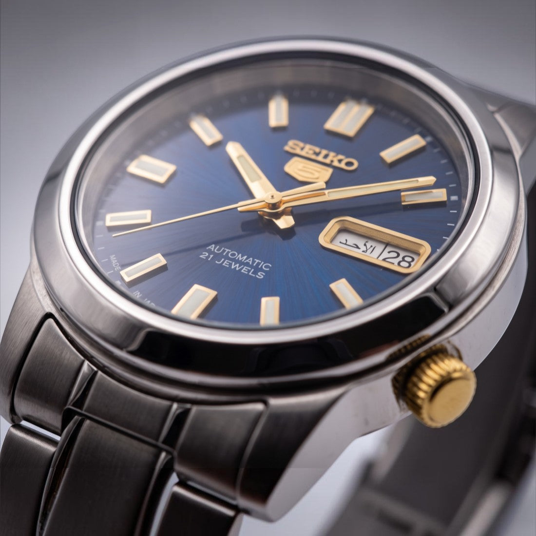 SUL EXTRAS Seiko 5 automatic watch with a midnight blue sunburst dial, gold indices, and Arabic day-date display.