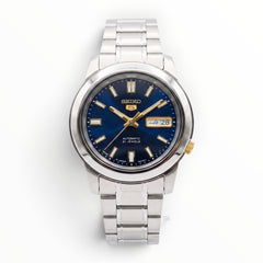 SUL EXTRAS Seiko 5 automatic watch with a midnight blue sunburst dial, gold accents, and silver stainless steel band.