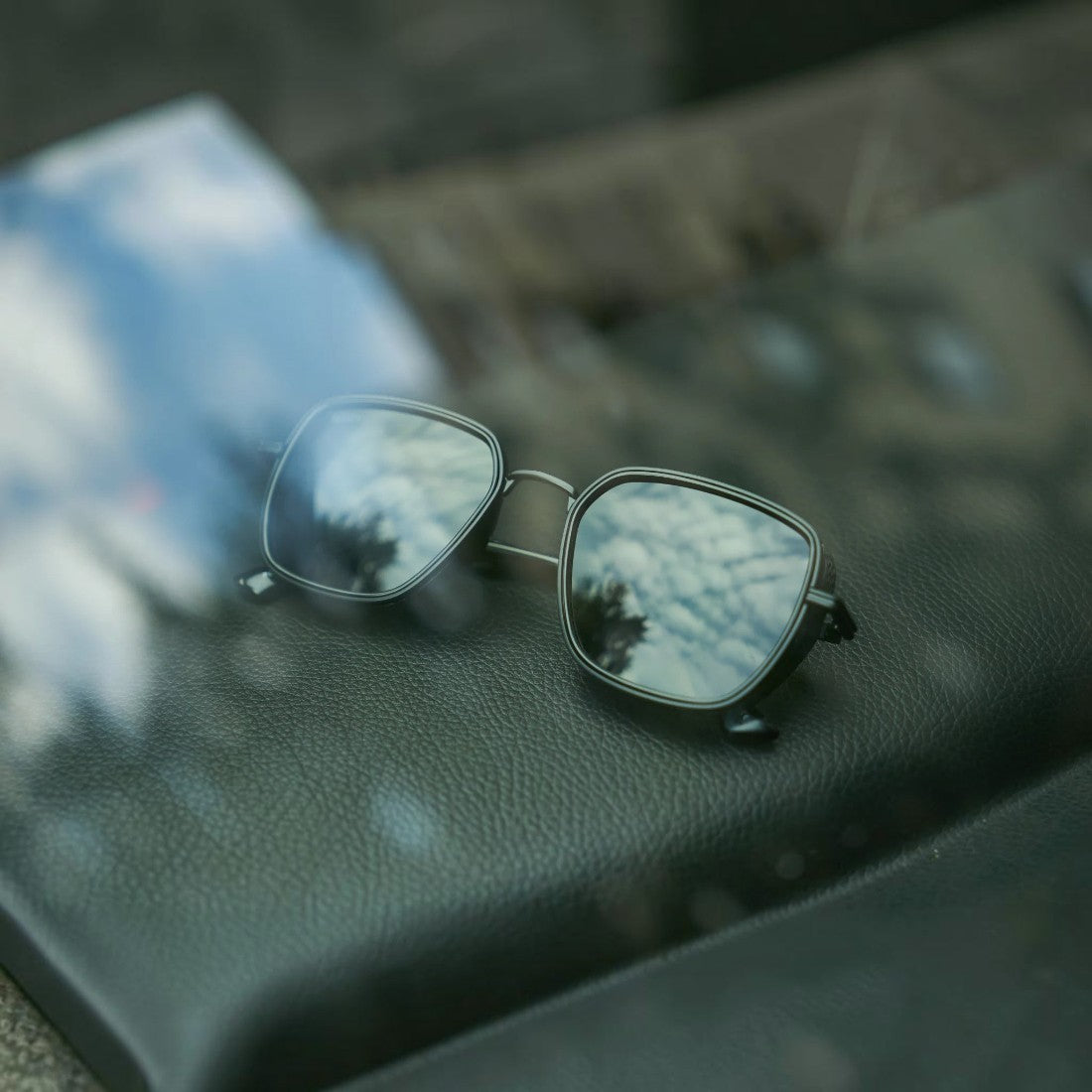 SUL EXTRAS Spark polarized sunglasses with black frames and reflective lenses resting on a textured surface