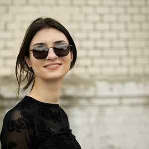 SUL EXTRAS Terra angular polarized sunglasses with a black metal frame worn by a woman against a brick wall background