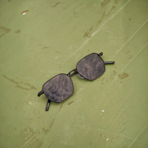 SUL EXTRAS Terra angular black polarized sunglasses with a durable metal and plastic frame on a green surface