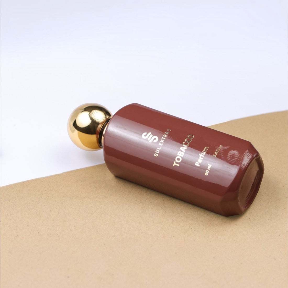 SUL EXTRAS Tobacco Parfum bottle in a deep brown glass with a gold cap, resting on a textured tan surface.