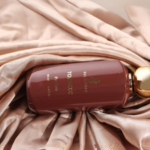 SUL EXTRAS Tobacco perfume bottle in a deep brown glass with gold lettering, resting on elegant champagne silk fabric.